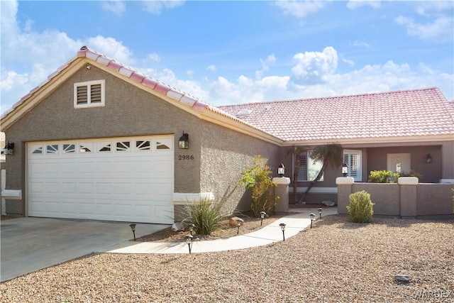 view of front of house featuring an attached garage, a tiled roof, concrete driveway, and stucco siding