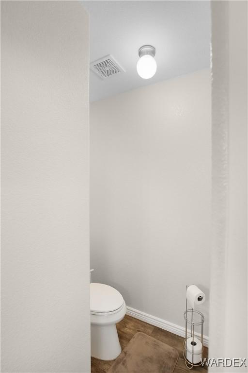 bathroom featuring toilet, baseboards, and visible vents