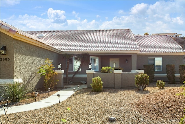 view of front facade with a tile roof and stucco siding