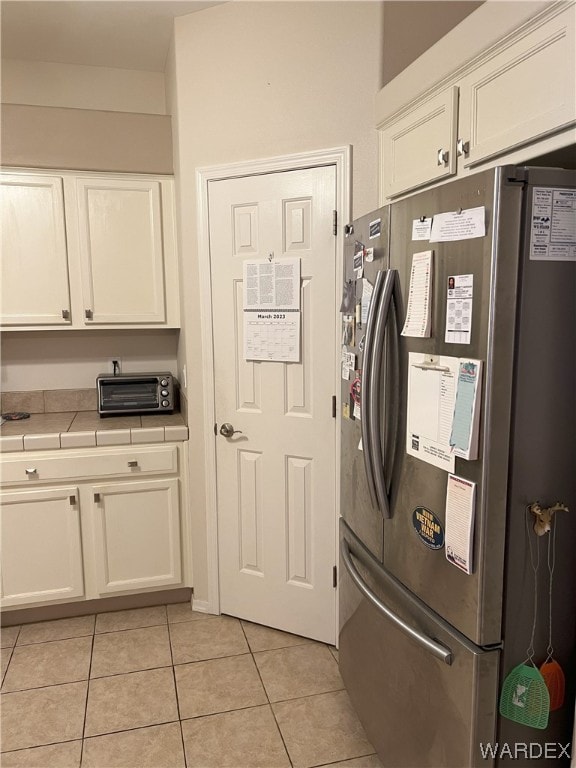 laundry area featuring a toaster, cabinet space, and light tile patterned floors