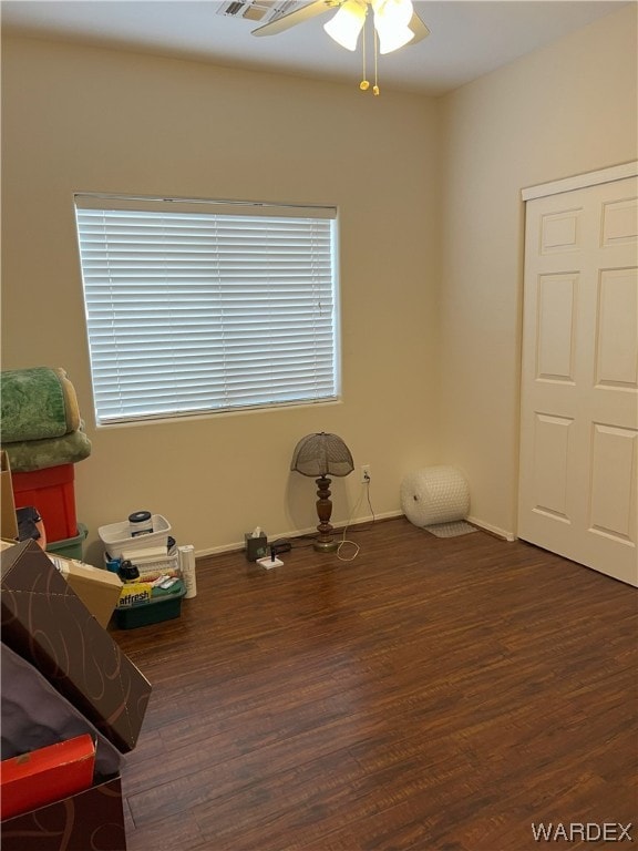 misc room with dark wood-style flooring, ceiling fan, and baseboards