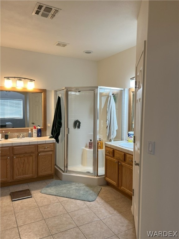 full bath with a stall shower, two vanities, a sink, and tile patterned floors