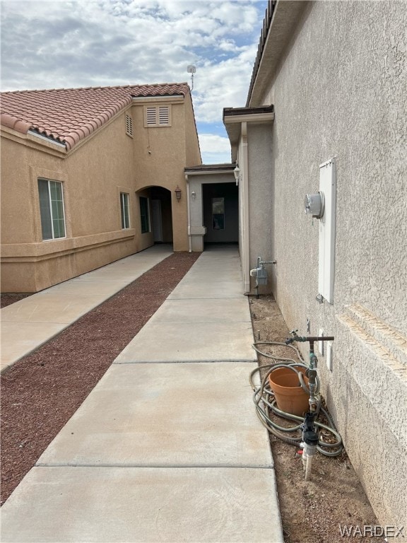 view of side of property with a tiled roof, a patio area, and stucco siding