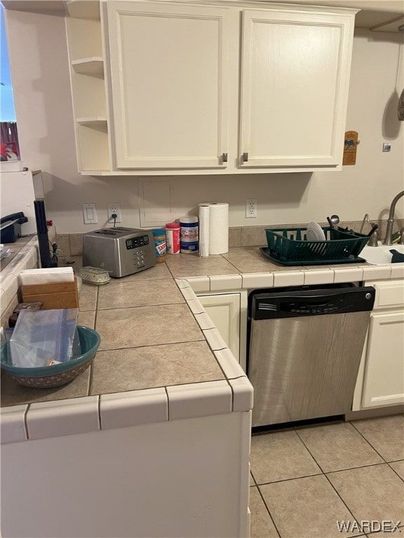 kitchen featuring tile countertops, light tile patterned flooring, white cabinetry, stainless steel dishwasher, and open shelves