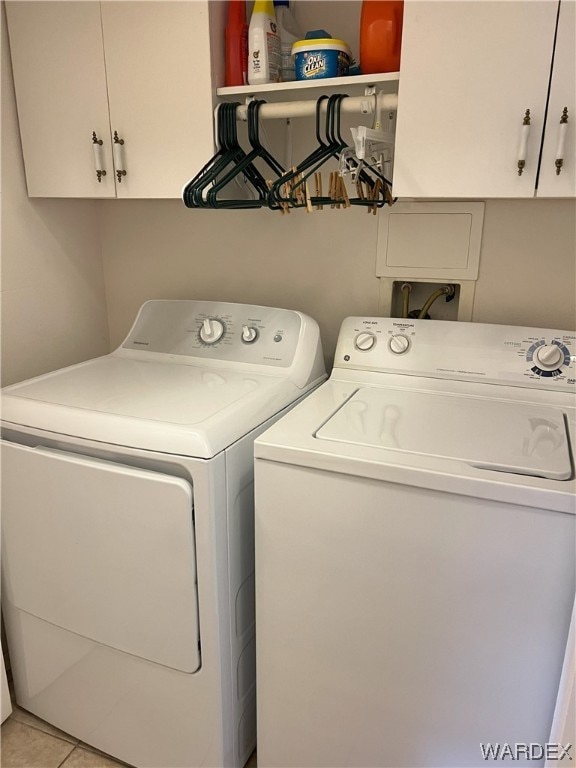 washroom with light tile patterned floors, washing machine and dryer, and cabinet space