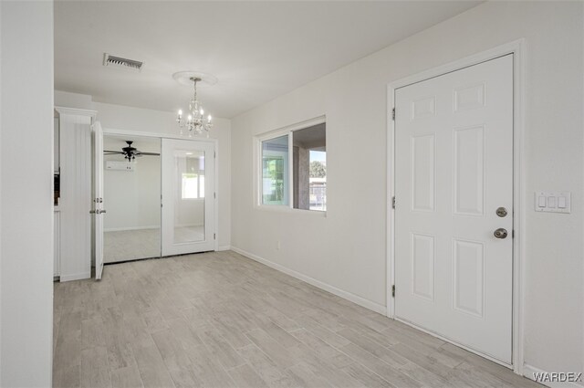 unfurnished room featuring light wood-type flooring, an inviting chandelier, visible vents, and baseboards