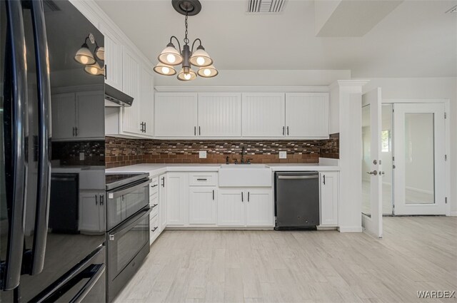 kitchen with light countertops, visible vents, white cabinets, a sink, and black appliances