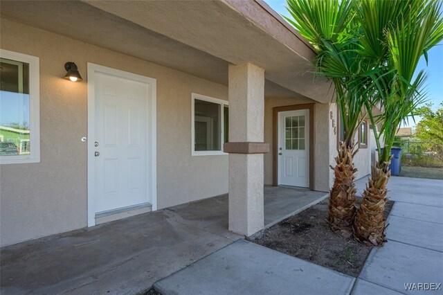 view of exterior entry featuring a patio and stucco siding