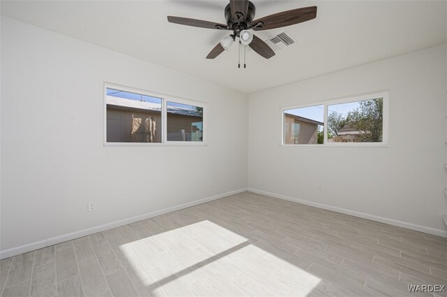 unfurnished room with light wood-style flooring, a ceiling fan, visible vents, and baseboards