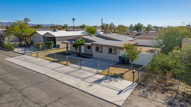 view of front of property with a fenced front yard, concrete driveway, a residential view, a gate, and stucco siding