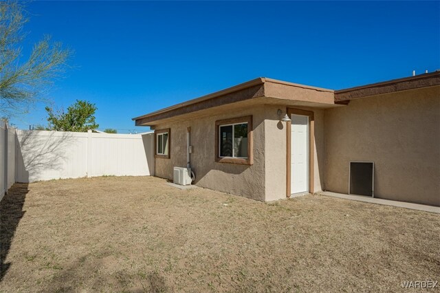 rear view of house with a fenced backyard and stucco siding