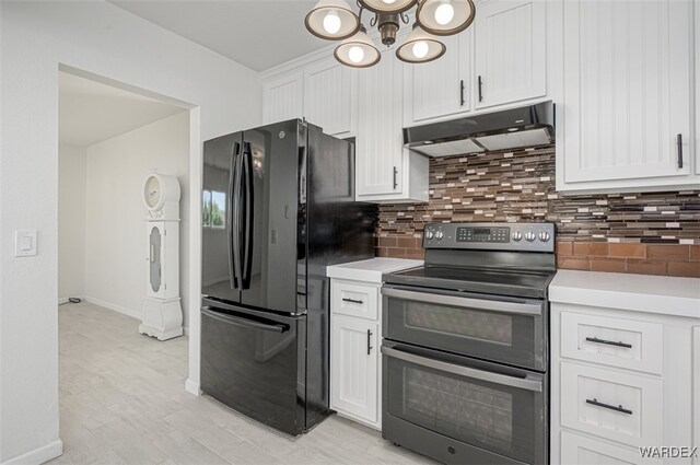 kitchen with range with two ovens, freestanding refrigerator, light countertops, and under cabinet range hood