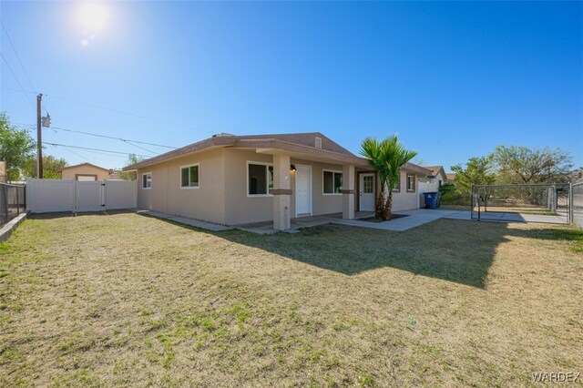 back of property with a gate, a fenced backyard, a lawn, and stucco siding