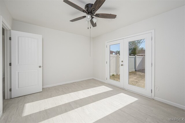 empty room with light wood-style flooring, baseboards, a ceiling fan, and french doors