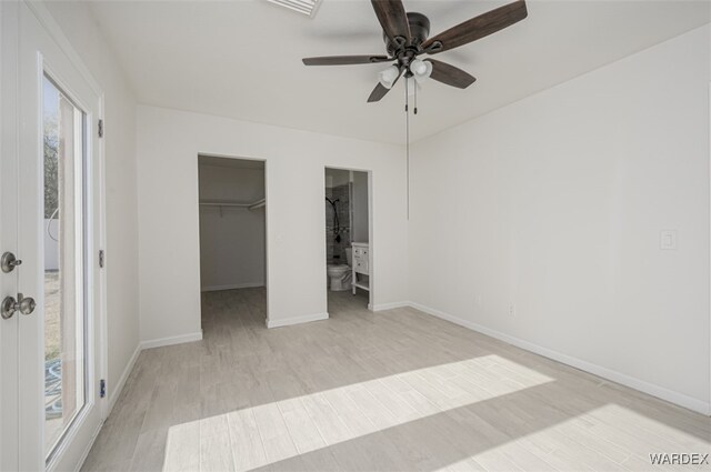 unfurnished bedroom featuring baseboards, a walk in closet, french doors, light wood-type flooring, and a closet