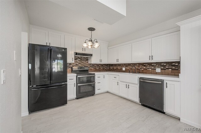 kitchen with stainless steel appliances, light countertops, hanging light fixtures, a sink, and under cabinet range hood