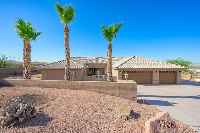 view of front of home featuring concrete driveway, a tiled roof, an attached garage, and stucco siding