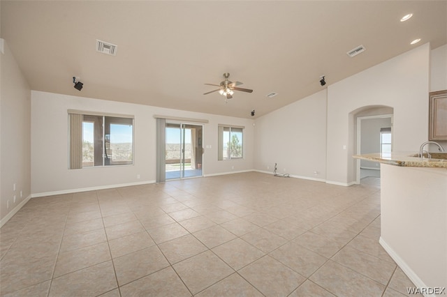 unfurnished living room with light tile patterned floors, lofted ceiling, visible vents, a ceiling fan, and a sink