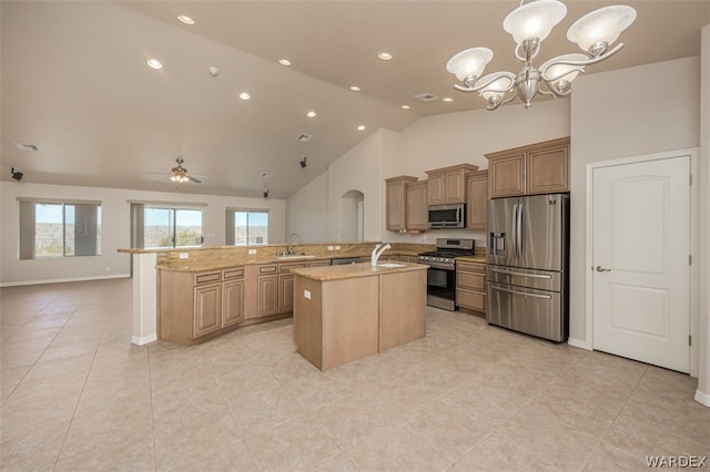 kitchen featuring a center island with sink, light stone counters, open floor plan, stainless steel appliances, and a sink