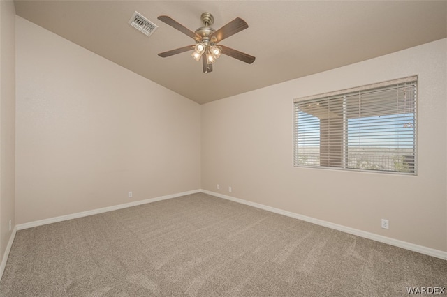 carpeted empty room featuring lofted ceiling, baseboards, visible vents, and a ceiling fan