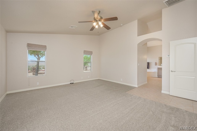 empty room with light carpet, baseboards, visible vents, and arched walkways