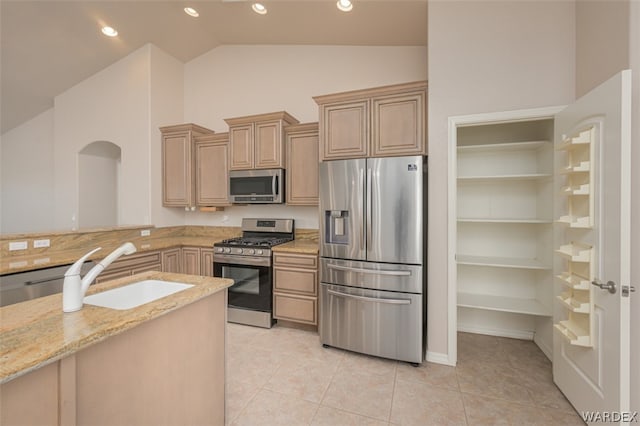 kitchen with light tile patterned flooring, light brown cabinets, a sink, appliances with stainless steel finishes, and light stone countertops