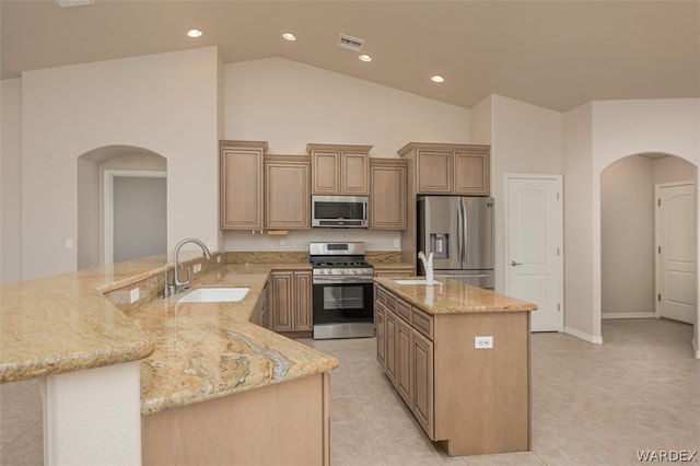 kitchen featuring appliances with stainless steel finishes, arched walkways, a peninsula, and an island with sink