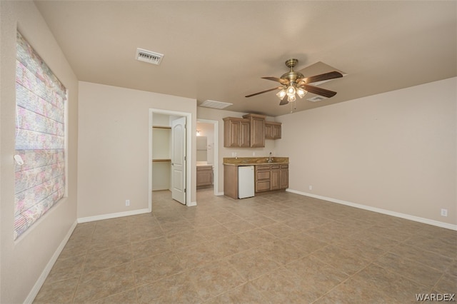 unfurnished living room with baseboards, visible vents, ceiling fan, and a sink