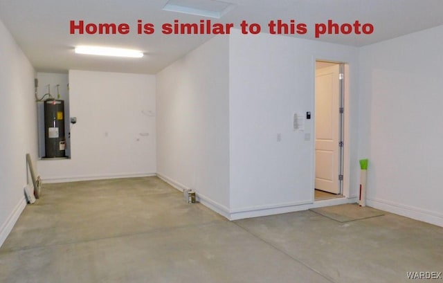 spare room featuring concrete flooring, electric water heater, and baseboards