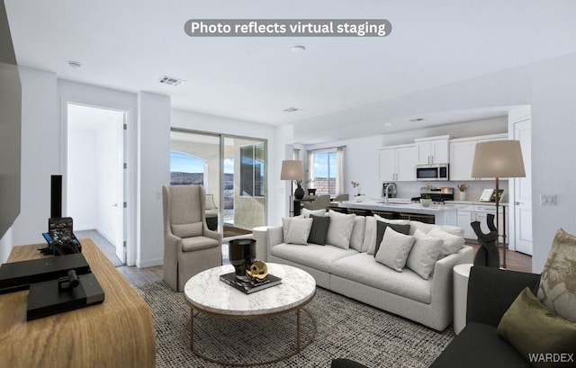 living room featuring light wood-style flooring, visible vents, and baseboards