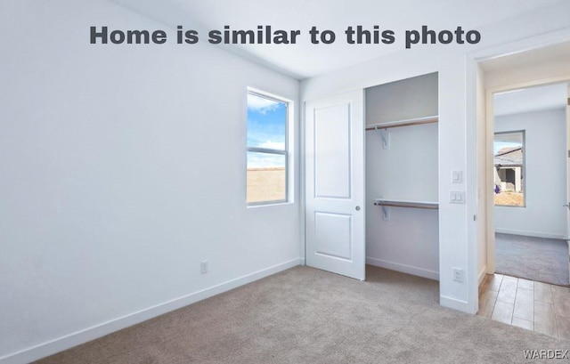 unfurnished bedroom featuring baseboards, a closet, and light colored carpet