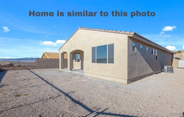 view of front of home with a fenced backyard, a tile roof, central AC, and stucco siding