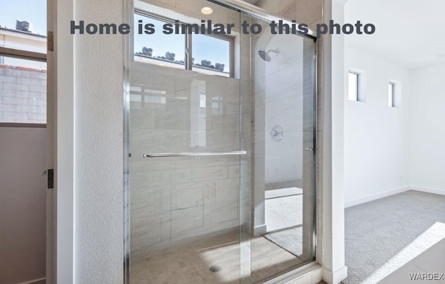 bathroom with a wealth of natural light, a shower stall, and baseboards