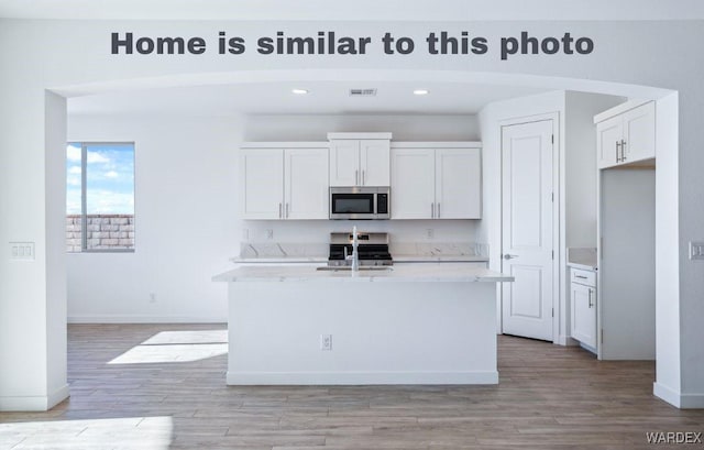 kitchen featuring white cabinets, a center island with sink, and stainless steel appliances