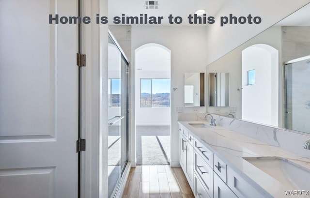 full bath with double vanity, a sink, visible vents, and a shower with door