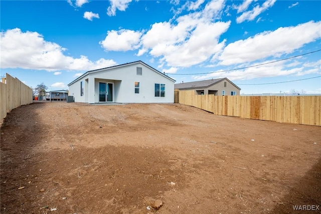 rear view of property with stucco siding and fence