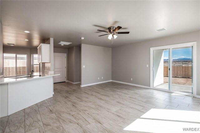 unfurnished living room featuring ceiling fan, a wealth of natural light, and visible vents