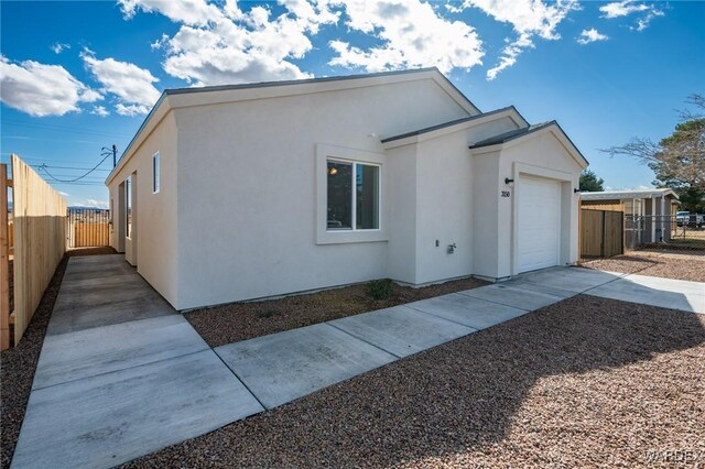 ranch-style house with an attached garage, fence, concrete driveway, and stucco siding