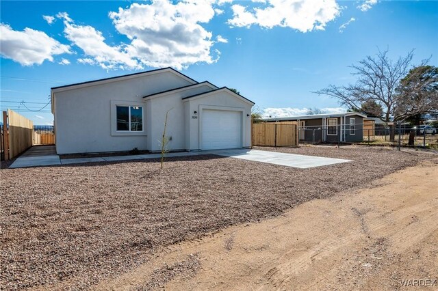 view of front of house with a garage, fence, driveway, and stucco siding