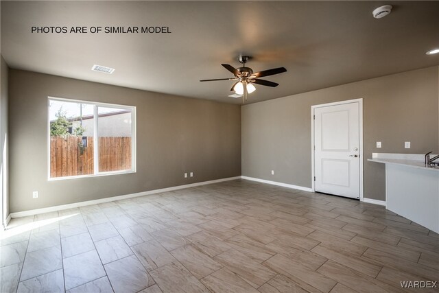 spare room featuring ceiling fan, visible vents, and baseboards