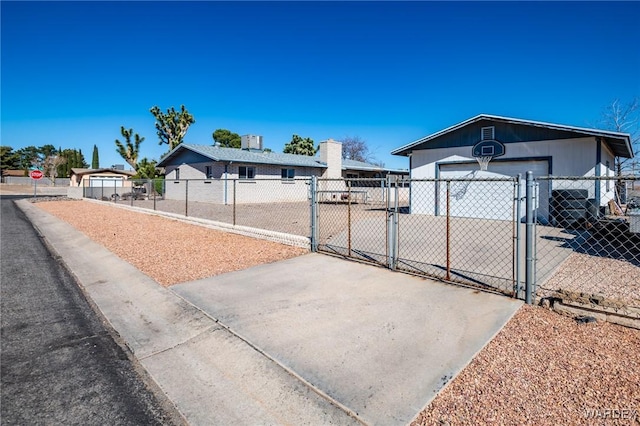 exterior space with a gate, fence, concrete driveway, and an outdoor structure