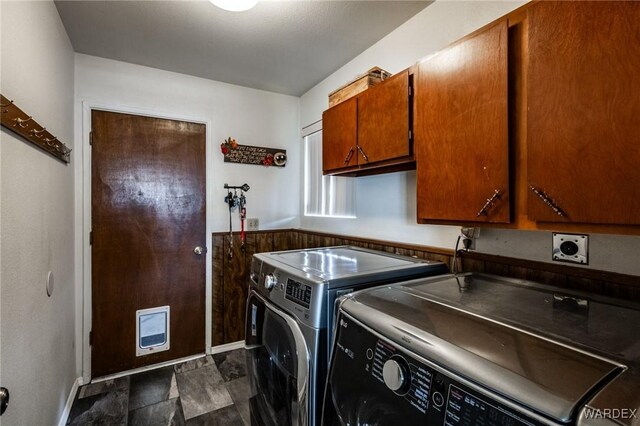 washroom featuring washing machine and dryer, stone finish floor, cabinet space, and baseboards