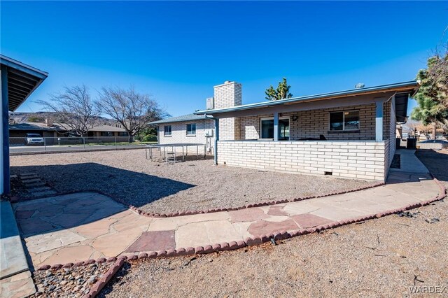 ranch-style house featuring brick siding, fence, and a chimney