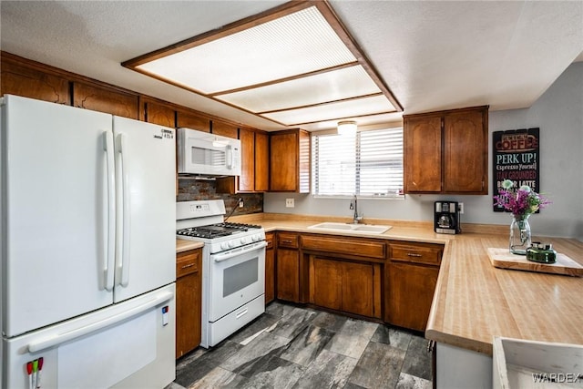 kitchen featuring brown cabinetry, white appliances, light countertops, and a sink