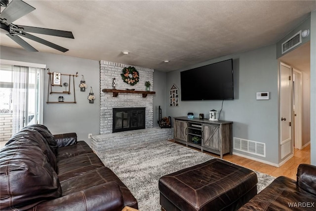 living room featuring a fireplace, wood finished floors, visible vents, and baseboards