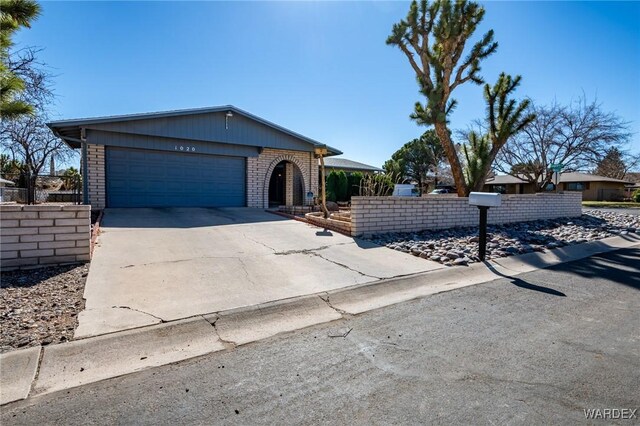 view of front facade with brick siding, driveway, an attached garage, and fence