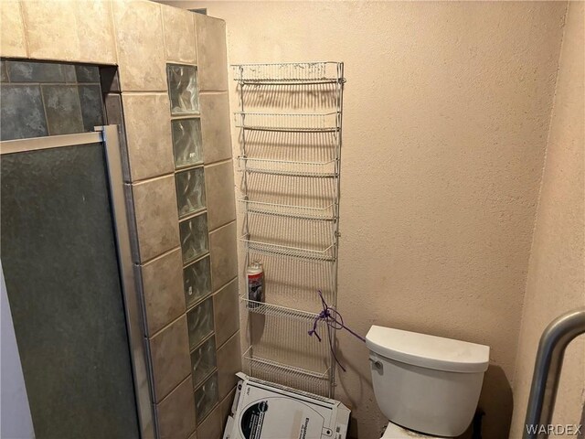 full bathroom featuring toilet and a textured wall