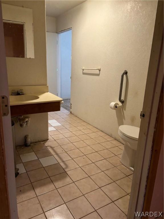 half bath with a sink, tile patterned flooring, and toilet