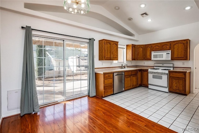 kitchen with visible vents, a chandelier, vaulted ceiling, brown cabinets, and white appliances