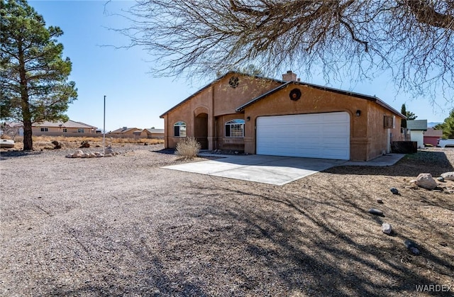 view of front of property with an attached garage, a chimney, and concrete driveway